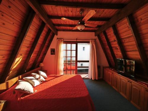 a bedroom with a red bed with a ceiling fan at Alpino Mitre in Mar de Ajó