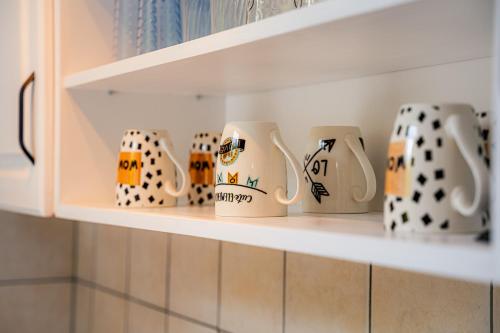 a row of coffee mugs sitting on a shelf at Apartman Gnječ Kupres in Kupres