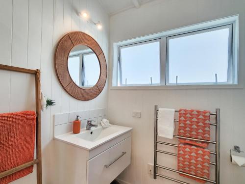 a bathroom with a sink and a mirror at Seashell Cottage Hahei in Hahei