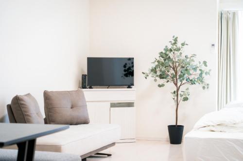 a white living room with a white couch and a tree at Greenfield - Vacation STAY 20427 in Sasebo