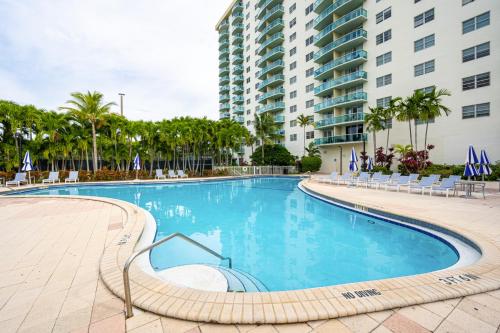 a large swimming pool with chairs and a building at Ocean Reserve Condo by FlatsAway in Miami Beach