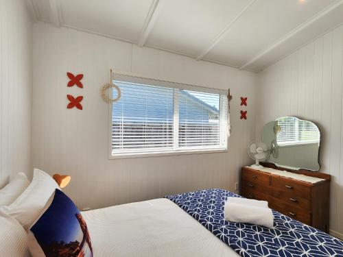 a bedroom with a bed and a window and a mirror at Seashell Cottage Hahei in Hahei