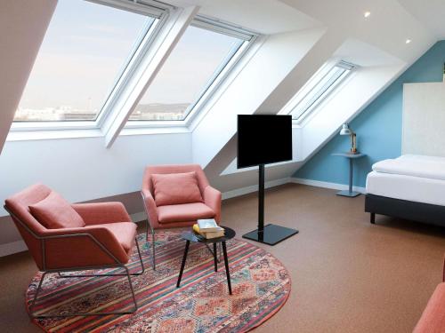 a attic living room with two chairs and a tv at greet Wien City Nord in Vienna