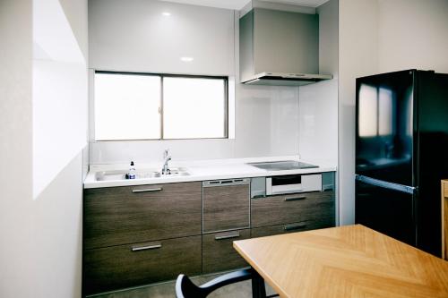a kitchen with a table and a sink and a refrigerator at Nostalgia Oiso Awaji - Vacation STAY 66330v in Kusumoto