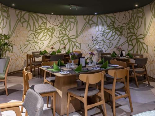 een eetkamer met tafels en stoelen met planten aan de muur bij Mercure Nairobi Upper Hill in Nairobi