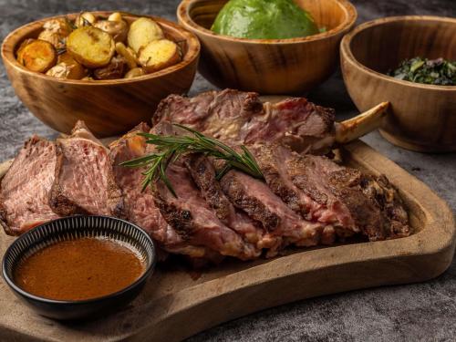 um bife em uma tábua de corte com batatas e outros alimentos em Mercure Nairobi Upper Hill em Nairobi