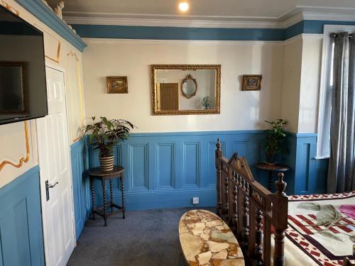 a room with blue walls and a staircase with a mirror at PERiVALE LODGE in Folkestone