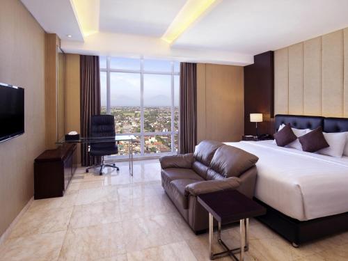 a hotel room with a bed and a couch at Grand Mercure Solo Baru in Solo