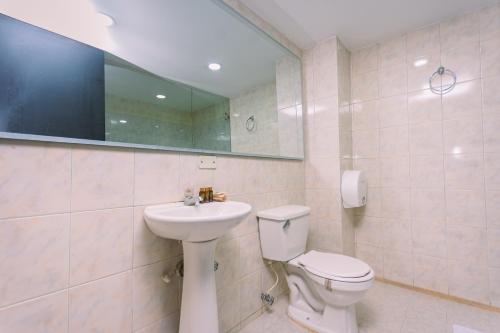 a bathroom with a sink and a toilet and a mirror at Mandala Medellín Centro By GyC Hotels in Medellín