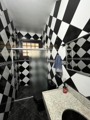 a bathroom with a black and white checkered wall at Casa do Guia - Casa compartilhada in Ouro Preto