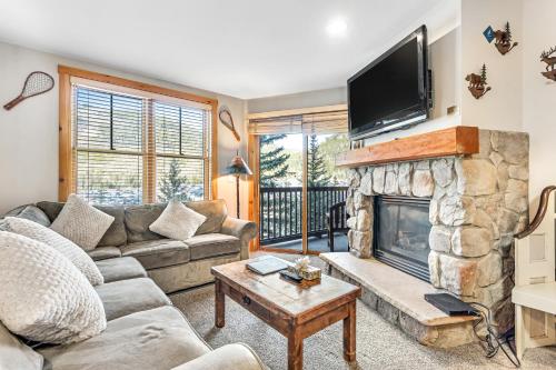 a living room with a stone fireplace with a flat screen tv at Buffalo Lodge 8351 in Keystone