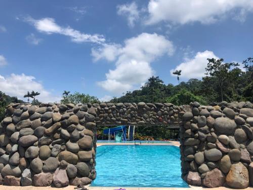 een zwembad in een resort met een stenen muur ernaast bij Alma y Palma Casa Campestre in Pedro Vicente Maldonado
