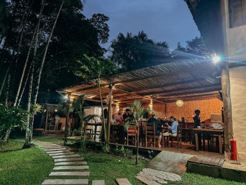 a group of people sitting at a table under a pergola at Pousada Aimê Maresias in São Sebastião