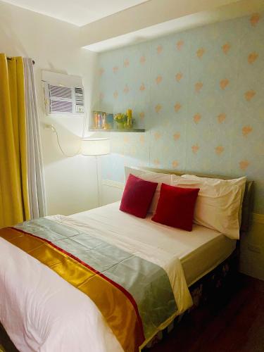 バコロドにあるMesavirre Garden Residences Tower B Studio Unitの赤い枕が2つ付いたベッドのある寝室