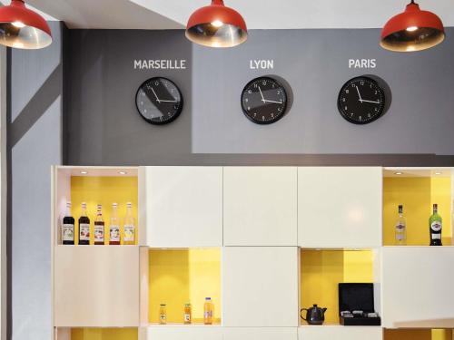 three clocks on a wall with bottles of wine at ibis Styles Marseille Gare Saint-Charles in Marseille