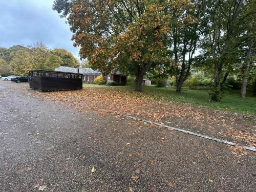 a bench sitting on the side of a road with leaves at Luxury 1 Bedroom Flat in Great Location in Bicester