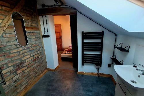 a bathroom with a sink and a brick wall at Stara Szkoła S7 Noclegi Mazury, Zajezierze 8 14-330 Małdyty in Małdyty