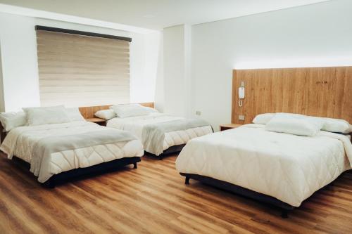 ドゥイタマにある24seven Hotel Boutiqueの木製の床の部屋にベッドが2つあります