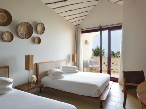 a bedroom with two beds and a balcony at Movenpick Resort Lamantin Saly in Saly Portudal