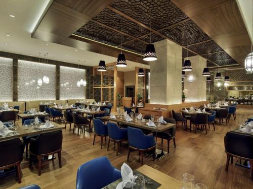 マラティヤにあるMovenpick Hotel Malatyaのダイニングルーム(テーブル、青い椅子付)