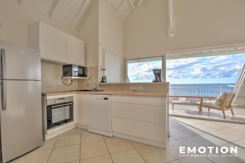 eine Küche mit weißen Geräten und Blick auf das Meer in der Unterkunft Deux pièces sur la belle plage de Grand Case in Grand Case
