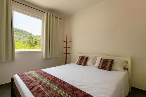 a bedroom with a large bed with a window at Cocanha Beach Pousadas in Caraguatatuba