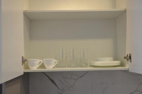 a white cabinet with cups and plates on a shelf at Condo en Cochabamba in Cochabamba
