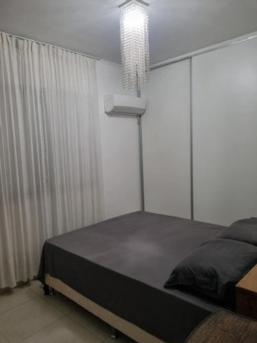 ein Schlafzimmer mit einem Bett und einem Kronleuchter in der Unterkunft Apto 2 quartos reformado centro in Cuiabá