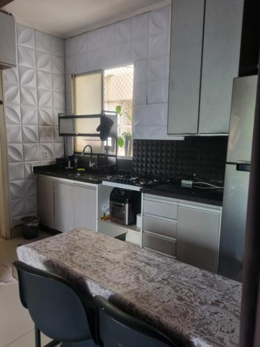 eine Küche mit weißen Schränken und einem Tisch mit Stühlen in der Unterkunft Apto 2 quartos reformado centro in Cuiabá