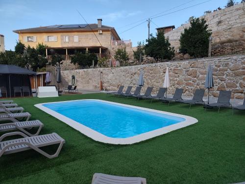 a swimming pool with lawn chairs and umbrellas at Quinta Cunha in São Pedro do Sul