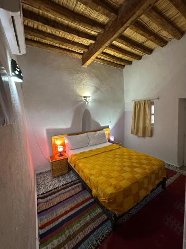 a bedroom with a yellow bed in a room at Riad Dar Zaouia in Zagora