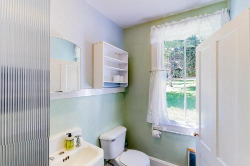 Un baño con inodoro, lavabo y ventana. en Garden Island's Birch, en Charlotte