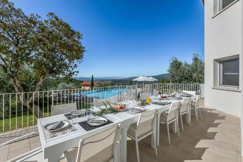 ein langer weißer Tisch und Stühle auf einer Terrasse mit Pool in der Unterkunft Amazing Villa Chimera White View Pool&Gym - Happy Rentals in Arezzo