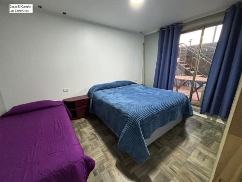 a bedroom with a purple bed and a window at Casas el Canelo in Isla Negra