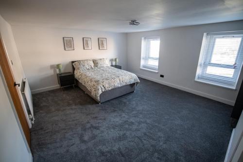 ein Schlafzimmer mit einem Bett und zwei Fenstern in der Unterkunft Cottage in Seaton in Siddick