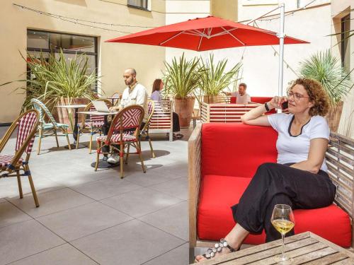 a woman sitting on a red couch on a patio at Aparthotel Adagio Montpellier Centre Comedie in Montpellier