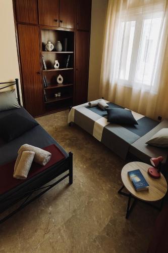 a bedroom with two beds and a table and a window at ElaPhos HOUSE in Kiriákion