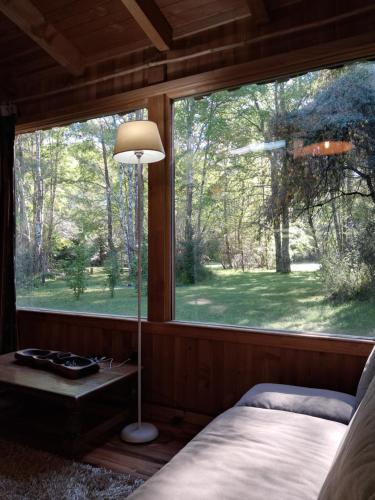 um quarto com uma grande janela com uma cama e um candeeiro em Domos Conguillío - Cabaña en el bosque em Melipeuco