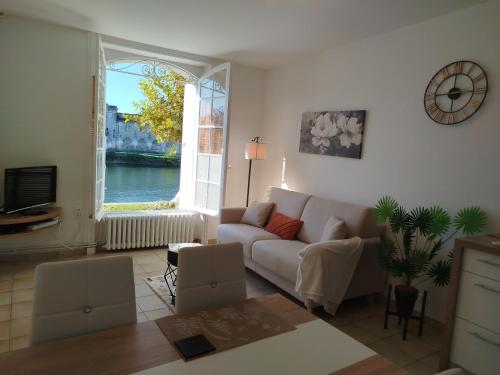 a living room with a couch and a window at Les appartements de l'Orangerie in Jarnac