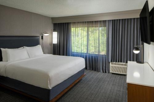 a hotel room with a bed and a large window at Courtyard Texarkana in Texarkana - Texas