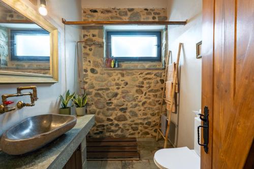 a bathroom with a sink and a stone wall at Doukas Village House in Gávros