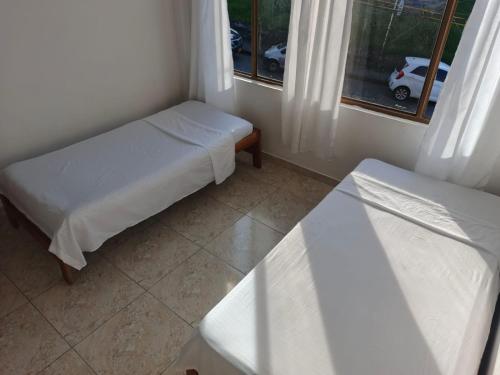 a small room with two beds and a window at Comodas y agradables Habitaciones en Chipre in Manizales