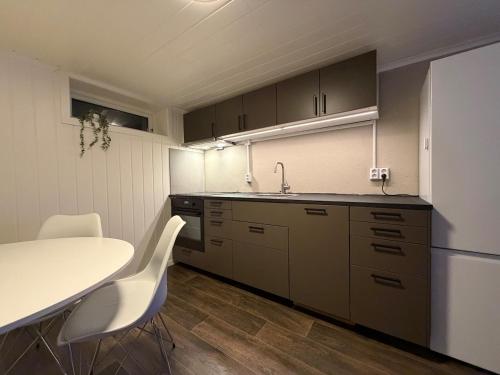 a kitchen with a table and white chairs in it at Ny leilighet i Stjørdal in Stjoerdal