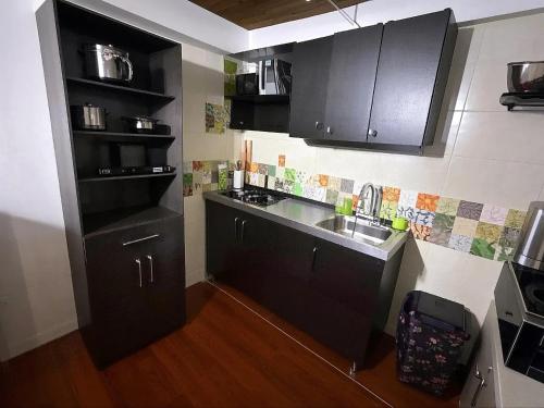 uma pequena cozinha com armários pretos e um lavatório em Aparta Suite Torre De Prado 305 em Medellín