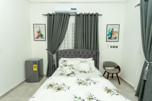 a bedroom with a bed and a chair and curtains at Welcome To Grand Central in Kwabenya