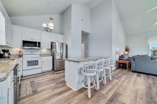 a kitchen with white cabinets and a bar with stools at Sea La Vie in Gulf Shores