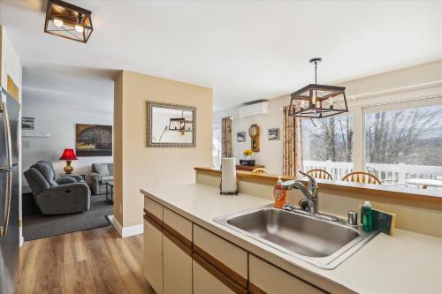 a kitchen with a sink and a living room at Mountainside Condo J201 in Stowe