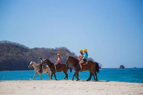a group of people riding horses on the beach at Morada Gaia in Tempate