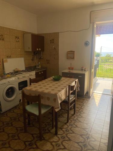 Una cocina con una mesa con sillas y una estufa. en Casa Vacanze Posidonia, en Agnone