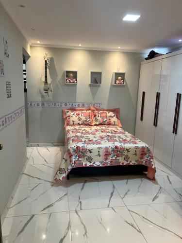a bedroom with a bed and a guitar on the wall at Chalé com Ar Condicionado Praia Seca in Araruama